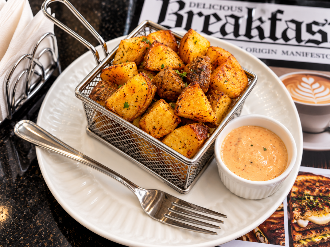 Seasoned potatoes in a wire basket with dipping sauce