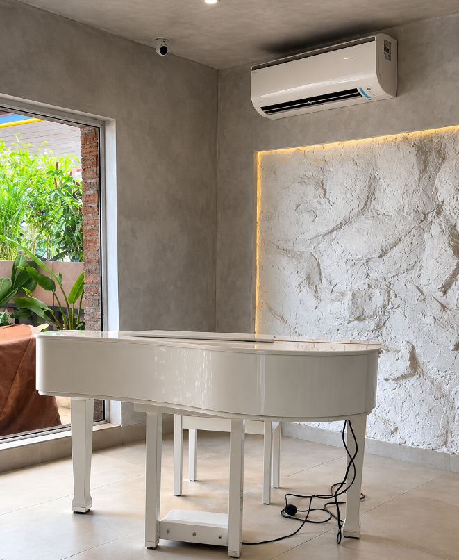 A white grand piano beside a lit textured wall